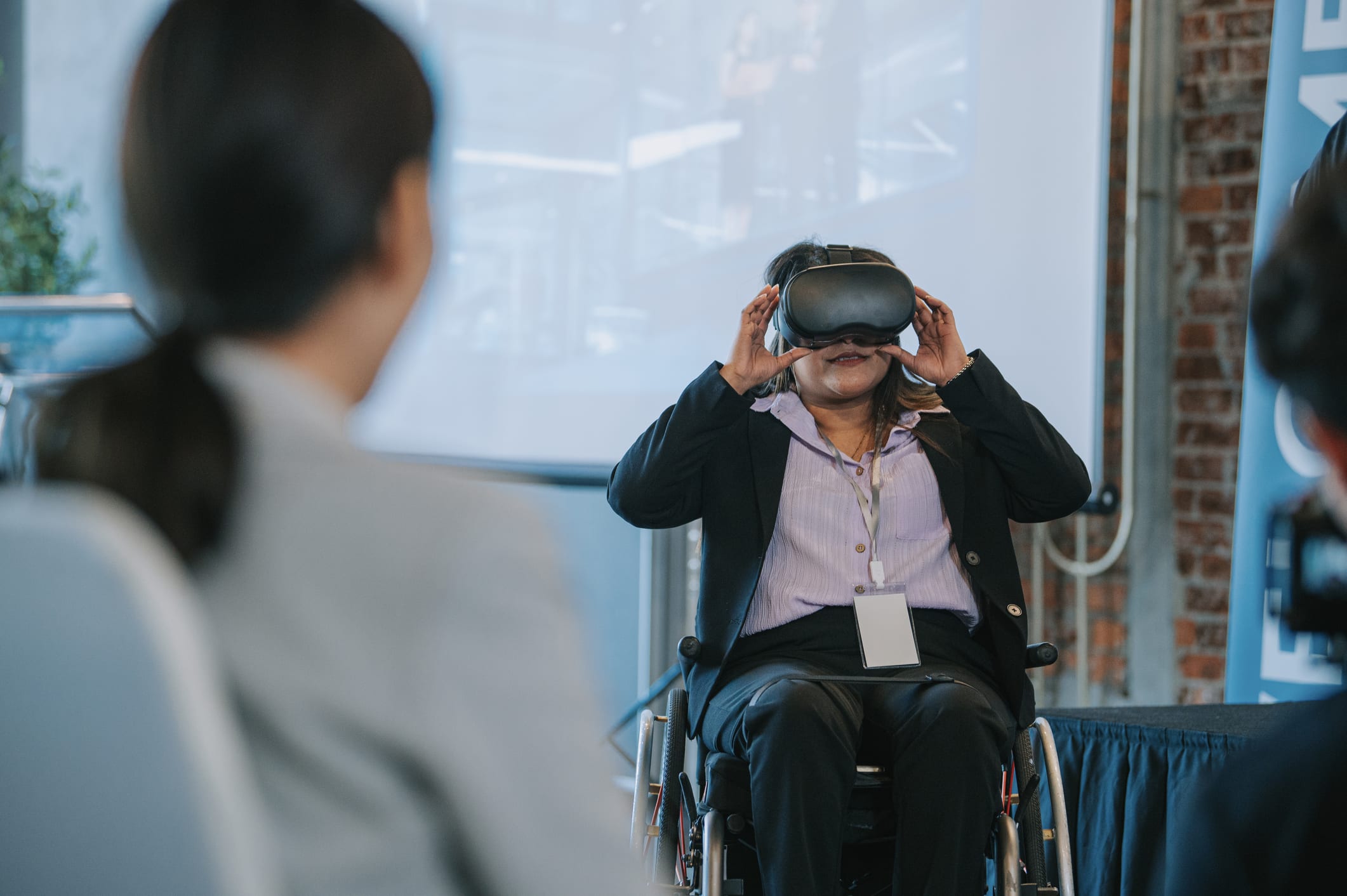 Asian Indian woman in wheelchair trying VR goggle during business conference seminar in convention center